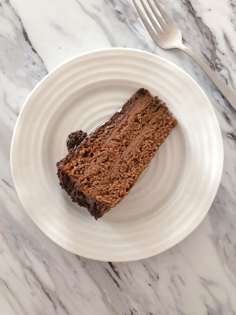 Once slice of chocolate truffle cake lying on its side on a white plate