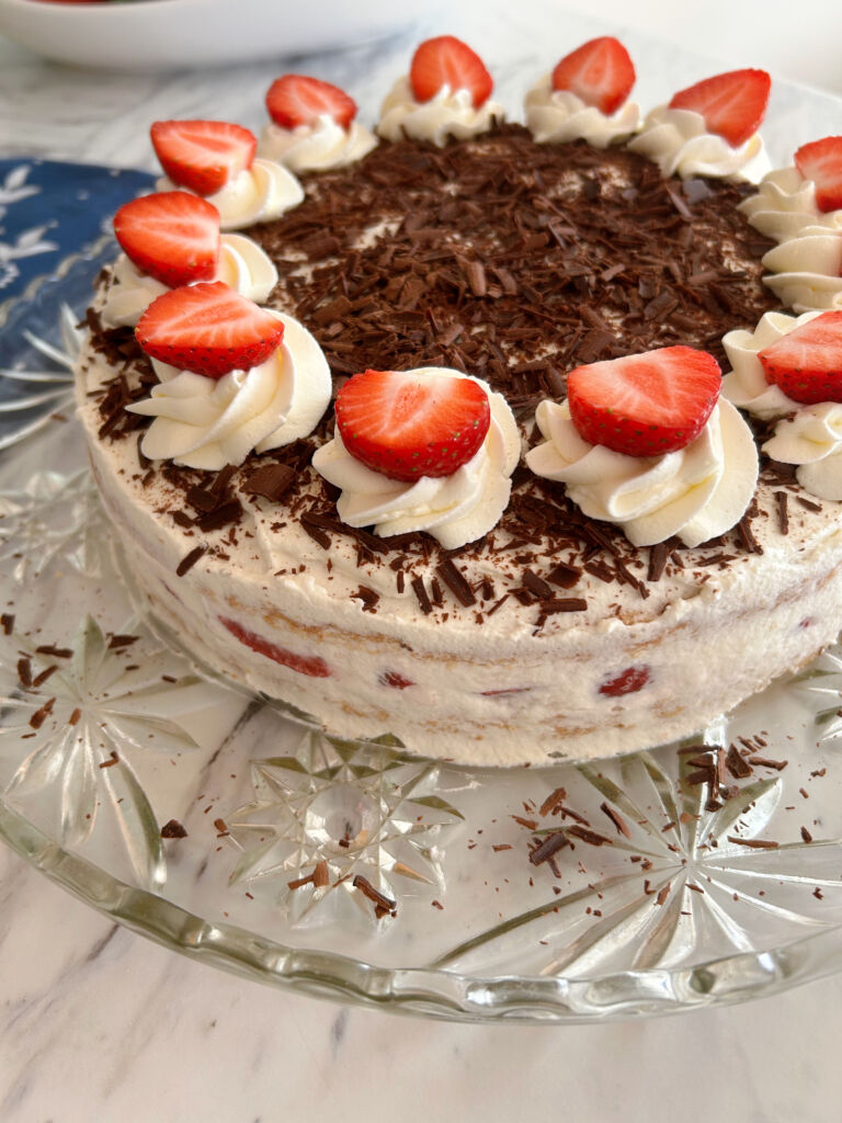 Side view of a german strawberry cream torte showing the cream and strawberries in between the two layers of cake.