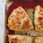 Cheddar, chive and herb spelt scones cooling on a baking tray with a silicone liner