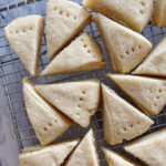 A bunch of Traditional Shortbread Wedge Cookies close together and cooling on a metal rack.