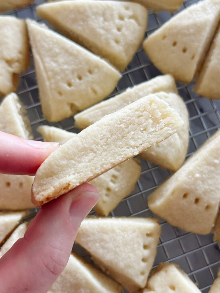 Close up of the side view of one Traditional Shortbread Wedge Cookies with all the others in the background cooling on a wire rack.