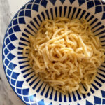 German Spätzle noodles piled high in a dark blue and white geometric patterned bowl.