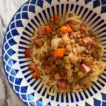 German Spätzle with Ham and Lentil Soup piled artfully in a dark blue and white geometric patterned bowl.